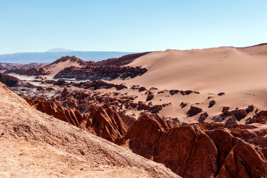 Reddish rock formations and sweeping sand dunes define the dramatic landscape of Moon Valley in Chile&rsquo;s Atacama Desert