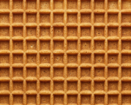 Geometric background texture of a crisp golden waffle cookie showing the structured grid pattern