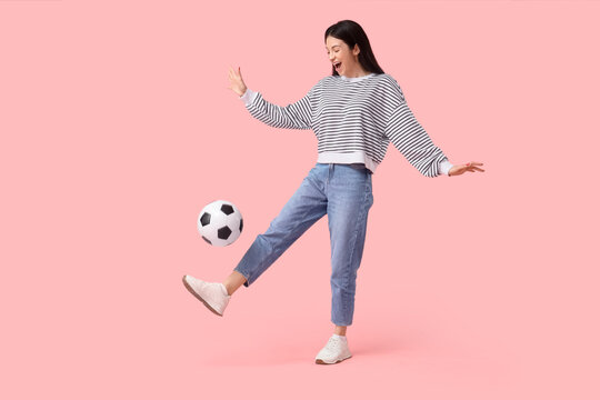Happy young woman playing with soccer ball on pink background. Sports bet concept