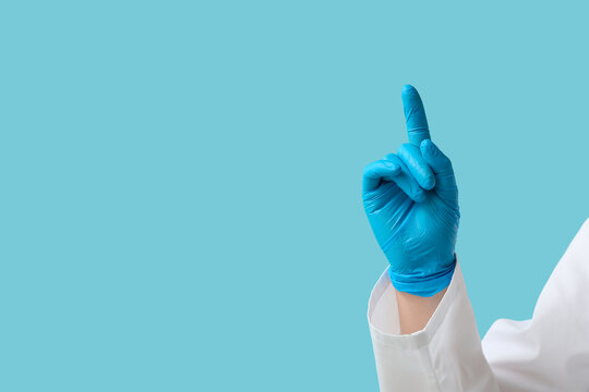 Doctor's hand pointing at something on blue background, closeup