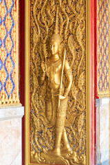 Fototapeta premium High relief guardian figure temple door Prasat Thong Kham Kanchanaphisek golden palace Wat Chantharam, ThaSung UthaiThani Thailand gilded ornament mirrored mosaic.