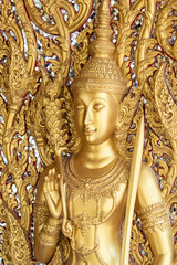 Fototapeta premium Close view ornate temple door golden thepphanom figure high relief layered carving sacred Thai ornament craftsmanship.