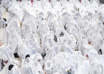 Fototapeta premium Hundreds of people sitting together covered with white fabric during a traditional spiritual ritual. Symbolic mass gathering expressing unity, faith, purity, and ceremonial devotion.
