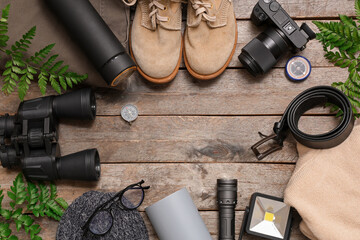 Fototapeta premium Frame made of different travel items, shoes, clothes and fern leaves on wooden background