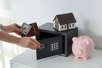 Woman putting money with passport in safe at home, closeup