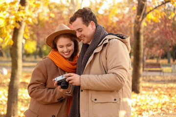 Fototapeta premium Beautiful loving young happy couple with photo camera in autumn park