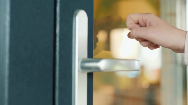 Hand knocking on glass door close up on door handle and knocking motion.
