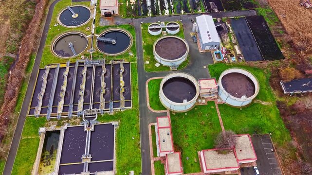 A large water treatment facility is visible, featuring multiple tanks and buildings arranged in a systematic layout. The area shows some greenery, indicating a mixed-use setting in a city.