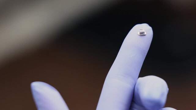 Single orthodontic metal bracket used in dental braces system displayed on fingertip highlighting precision engineered component designed for tooth alignment and controlled orthodontic correction