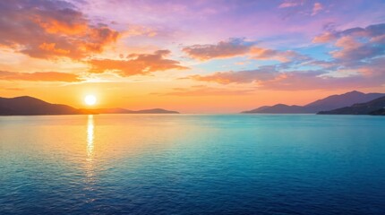 Fototapeta premium Golden sun setting over calm ocean waters with distant mountain silhouettes under a colorful sky filled with orange pink and purple clouds reflecting on the rippling sea surface at twilight