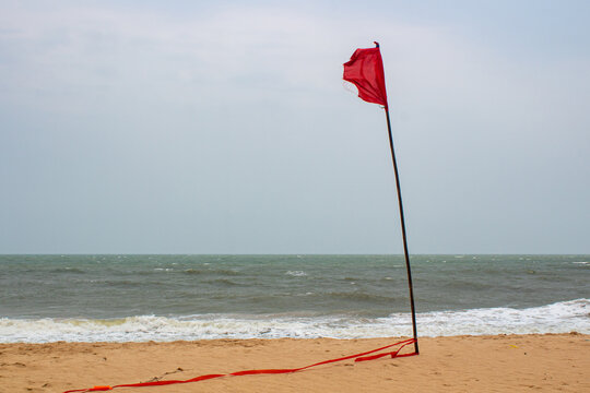 Red beach warning flag on sandy shoreline