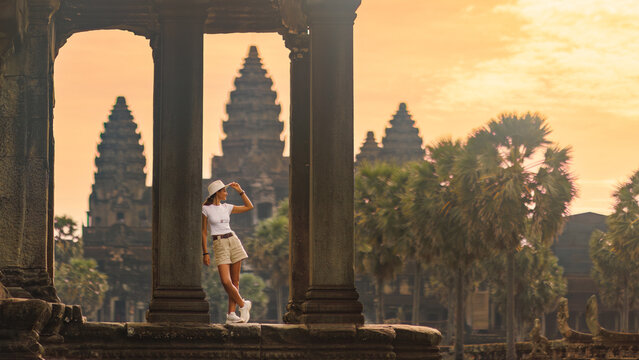 Stylish Female Tourist Admiring Angkor Wat Temple at Golden Sunrise