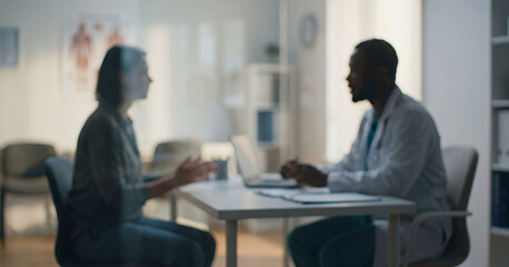 Fototapeta premium A healthcare professional engaged in a conversation with a patient in a medical office. The atmosphere is calm and focused on patient care.
