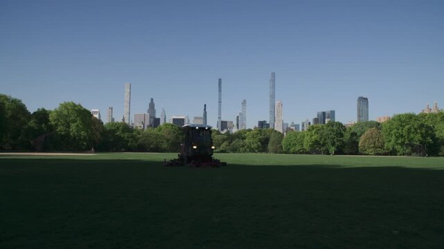 Handheld shot of a groundskeeper mowing the lawn in Central Park