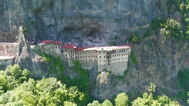 Altindere, Trabzon Province, Turkey. Sumela Monastery, a multi-story stone complex with red-tiled roofs built into a sheer cliff face, aerial drone view over lush green Altindere Valley. Aerial View,
