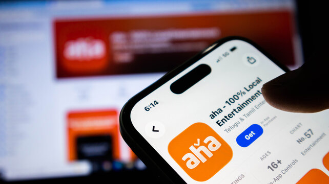 Closeup of a smartphone screen displaying the aha streaming app page in the apple app store, with a blurred background