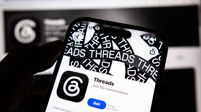 Closeup of a smartphone screen displaying the threads app download page on the apple app store, showing the app icon and get button