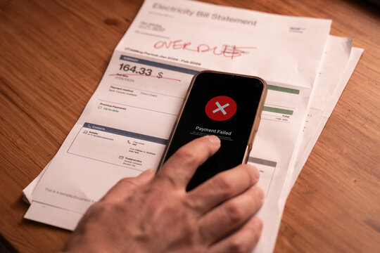 Failed bill payment on smartphone with overdue utility bill on table