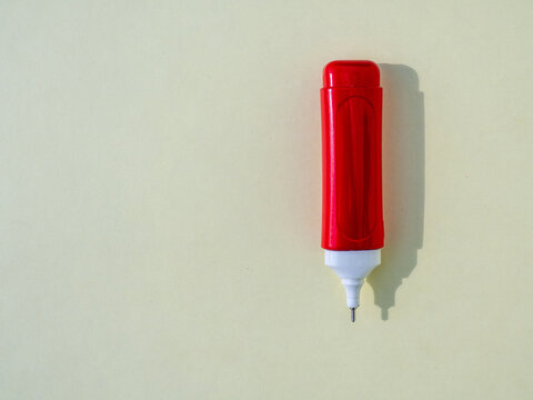 Red correction pen isolated on a light background with copy space. Minimal office and stationery concept, top view with soft shadow and clean composition