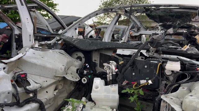 Electric car junkyard. Car beyond repair after accident. Car rusting in junkyard. Scrap metal being recycled. Dismantling of spare parts, scrap metal recycling.