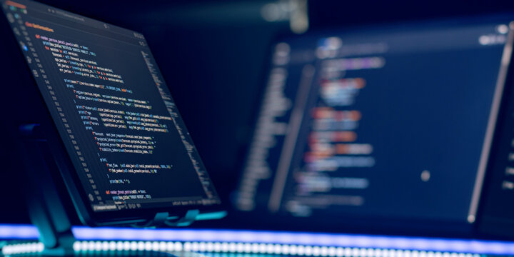 Software engineering workspace. Multiple screens showing complex coding script in dark mode, illuminated by glowing blue LED light. Cybersecurity concept.