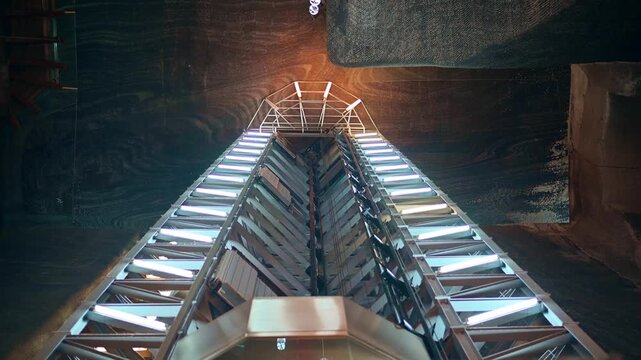 A long shot of the modern elevator in the turda salt mine romania moving up with multiple neon light on its sides.