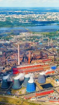 Vertical video. Lipetsk, Russia. Novolipetsk Iron and Steel Works, hyperboloid cooling towers and blast furnaces, aerial panoramic view over the Left Bank industrial district. Drone footage. Rich col