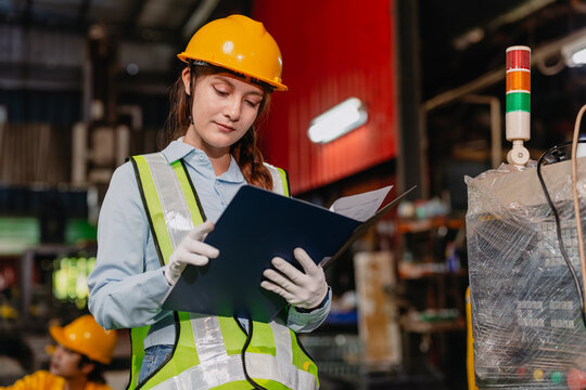 Professional Engineer female worker supervisor Reading in heavy industry metal factory with safety
