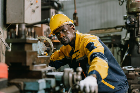 Professional African black Engineer male worker work with metal lathe machine in metal part factory