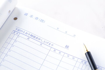 請求書 - 取引先に宛てた請求書を作成しているビジネスシーンのイメージ  © PJM