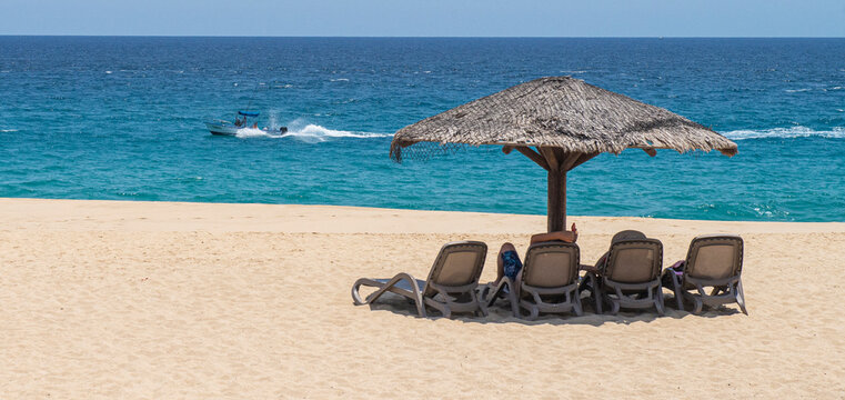 Cabo San Lucas Baja Califronia Sur, MEXICO, lugar turistico famoso en el sur de la peninsula. Palapa en la playa con el oceano pacifico al fodo, con lancha pasando al fondo.