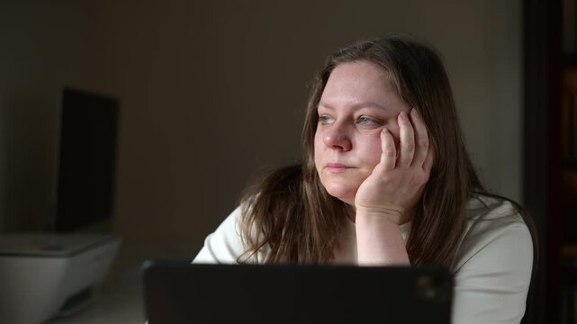 Exhausted woman looking away from laptop during remote work at home