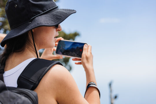Young woman takes selfie while hiking in mountainous area. Rocky