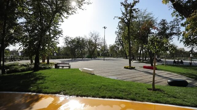 A walk along the shore of the city lake, planted with greenery and trees. There are fountains on the lake.
