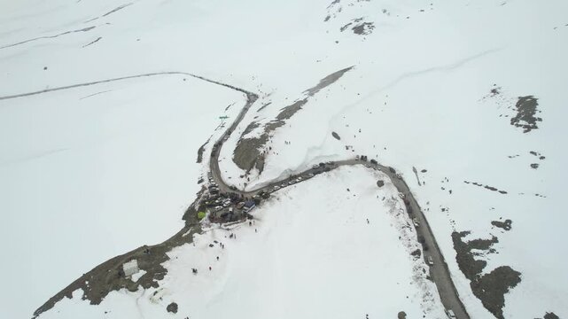 Aerial drone orbit wide view of tourists exploring snowy mountains near Shinkula Top Pass and Sissu in Himachal Pradesh with parked 4X4 vehicles winding roads in Ladakh Himachal Pradesh India during w
