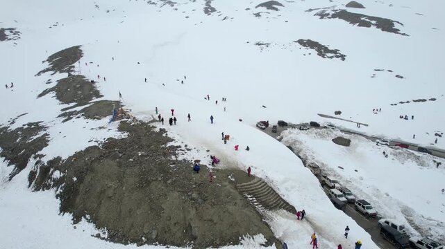 Aerial drone orbit view of tourists exploring snowy mountains near Shinkula Top Pass and Sissu in Himachal Pradesh with parked 4X4 vehicles on this critical road in Ladakh Himachal Pradesh India durin