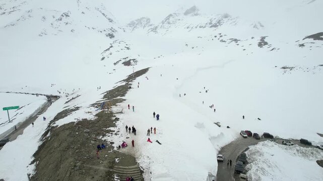 Aerial drone orbit view of tourists exploring snowy mountains near Shinkula Top Pass and Sissu in Himachal Pradesh with parked 4X4 vehicles on this critical road in Ladakh Himachal Pradesh India durin
