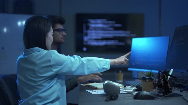 Two diverse programmers working together on a coding project in a modern office.