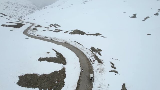 Aerial drone shot following the winding Shingo La pass road surrounded by snow covered fields among the Himalaya mountains showing the transport infrastructure in Ladakh Leh Sissu India
