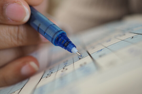 blue pen to fill out a structured form, likely for an academic exam or a standardized test.