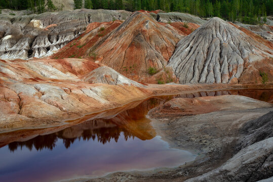 Reflection of the red mountains in an artificial lake. Refractory clay quarry (Ural Mars). Sverdlovsk Region, Russia