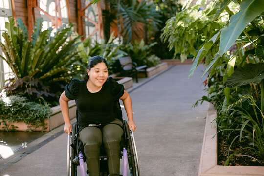Smiling woman in wheelchair on path in botanical garden
