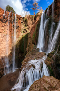 Majestic waterfalls cascading down red rock canyon walls in Morocco