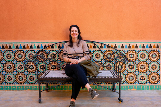 Smiling woman on colorful mosaic bench in Marrakesh, Morocco