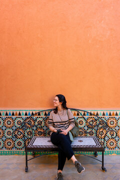 Smiling woman on colorful mosaic bench in Marrakesh, Morocco