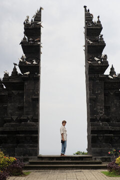 Woman standing in Balinese split gate with doves perched on top