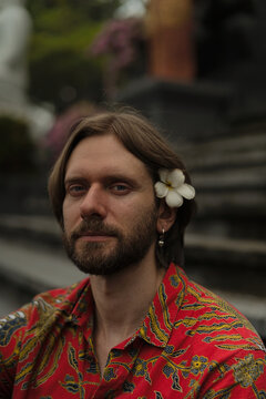 Bearded man with frangipani flower in hair at Balinese temple, Bali