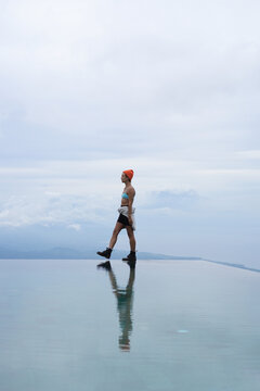 Stylish young woman walking along infinity pool edge, Munduk, Bali