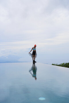 Pensive young woman at infinity pool with mountain view, Bali