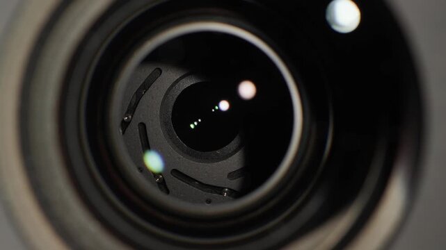 Macro video of professional camera lens aperture closing and opening with cinematic glass reflections.